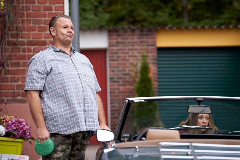 Kurt (Oliver Fleischer) poliert tänzelnd seinen Wagen zu Schlagermusik. – Bild: TVNOW /​ Guido Engels