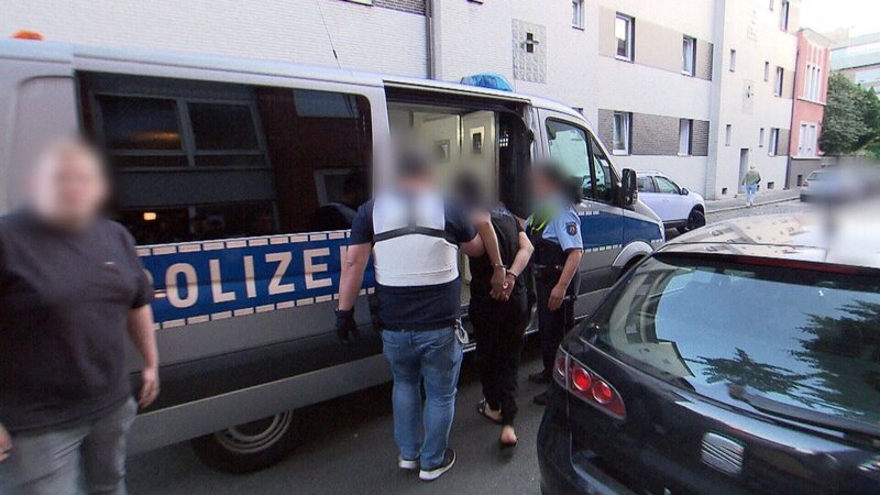 Razzia: Ein Tatverdächtiger des SMS-Betrugs wird von Polizisten in den Gefangenentransporter gebracht. – Bild: RTL /​ Extra Spezial: Jagd auf die SMS-Betrüger