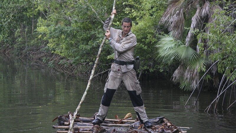 Bear Grylls stands on raft navigating down river using long stick. – Bild: Discovery Communications