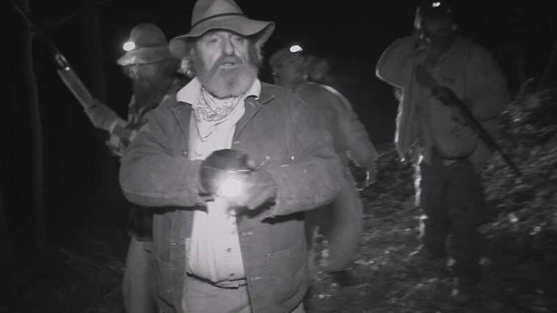 Ein Mann hält Licht in einem Wald – Bild: Warner Bros. Discovery