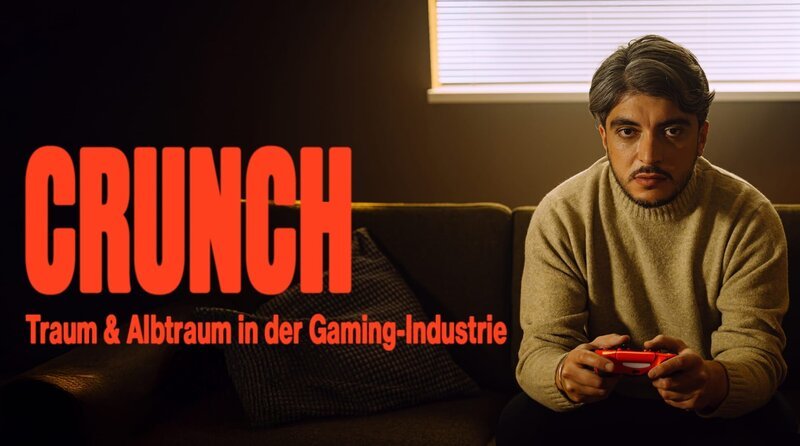 SÜDWESTRUNDFUNK Crunch – Traum und Albtraum in der Gaming-Industrie – In „Crunch“ erzählen Entwickler:innen nicht nur von ihrer Liebe zu Games – sondern auch von den oft ausbeuterischen Strukturen in der größten Unterhaltungsindustrie der Welt. Was kostet der Erfolg von Videospielen?: Host Khesrau Behroz sitzt mit Videospiel-Controller auf dem Sofa. © SWR, honorarfrei – Verwendung gemäß der AGB im engen inhaltlichen, redaktionellen Zusammenhang mit genannter SWR-Sendung und bei Nennung „Bild: SWR“ (S2+). SWR Presse/​Bildkommunikation, Baden-Baden, Tel: 07221/​929–22202, foto@swr.de – Bild: SWR