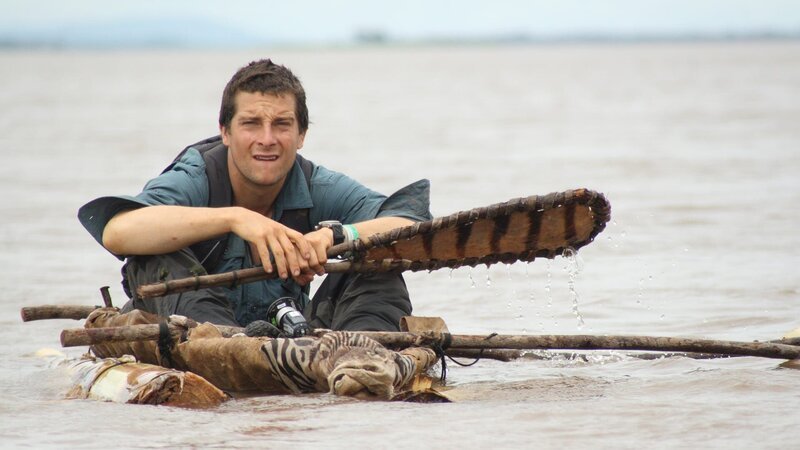 Bear Grylls sits in zebra skin canoe. – Bild: Warner Bros. Discovery