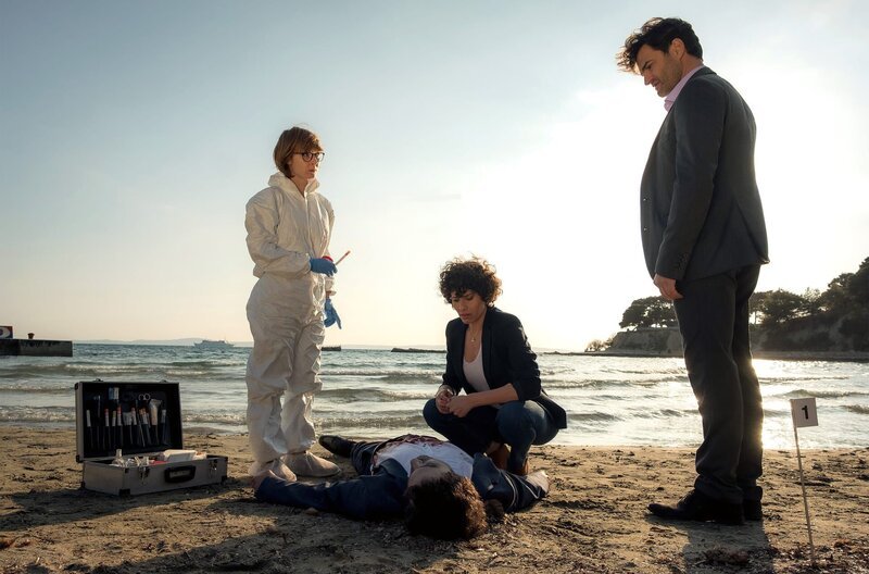 Pathologin Brigita Stevic (Sarah Bauerett, l.), Kommissarin Stascha Novak (Jasmin Gerat) und ihr Kollege Emil Perica (Lenn Kudrjawizki) untersuchen den Toten am Strand. – Bild: SWR/​ARD Degeto/​Constantin TV/​Conny Klein