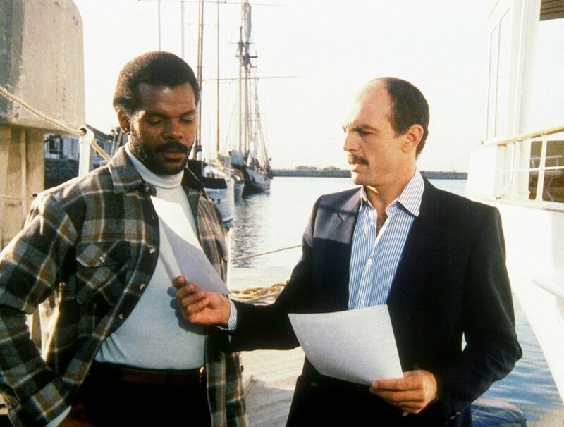 Dagget (Al White, l.) erhält von Pierce (Carmen Argenziano) Amandas Personenbeschreibung. Er soll die Agentin für einen reichen Kunden entführen. – Bild: CBS Television