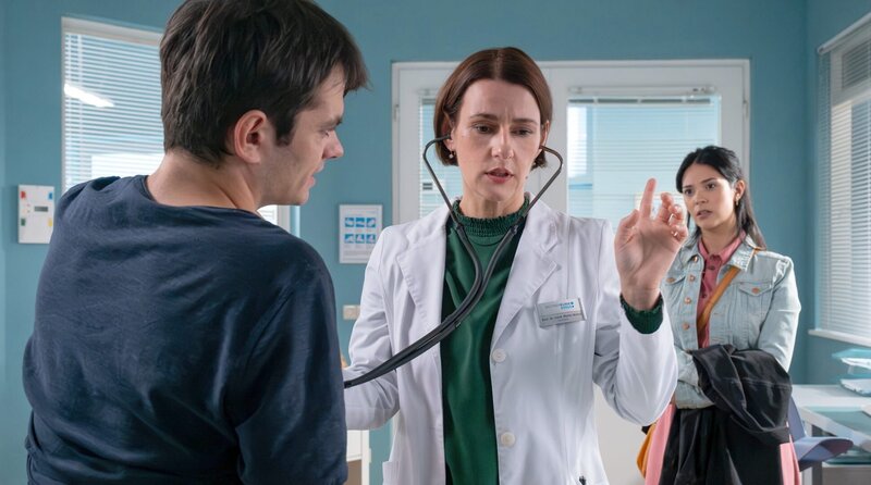 Mike Wiesinger (Anton Andreew, li.) geht es seit einem Infekt immer schlechter. Dr. Maria Weber (Annett Renneberg, mi.) versucht ihn zu untersuchen, doch Mikes Schwester Anna (Meryl Marty, re.) ist so in Sorge, dass sie jede Frage für ihn beantwortet und das auch dann, wenn keine gestellt wurde. – Bild: MDR/​Sebastian Kiss