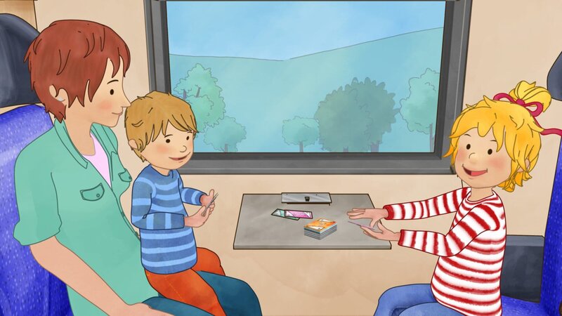 Conni findet Zugfahren klasse. Auf der Fahrt spielt sie mit Jakb und Mama Karten. – Bild: ZDF