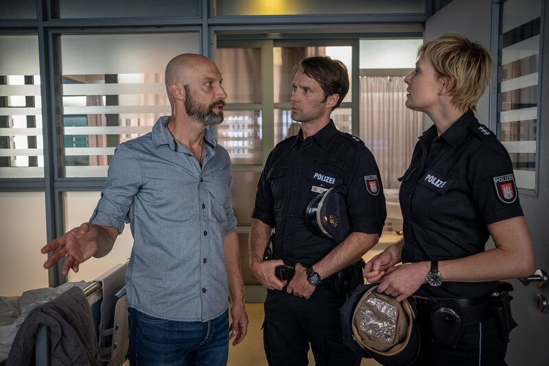 Torben Vogel (Andreas Grötzinger, l.) regt sich bei Mattes (Matthias Schloo, M.) und Melanie (Sanna Englund, r.) darüber auf, dass Maja mit einem Mann auf dem Krankenzimmer liegen muss. – Bild: ZDF und Boris Laewen