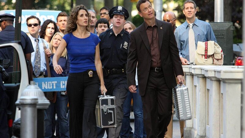 Die Detectives Stella Bonasera (Melina Kanakaredes) und Mac Taylor (Gary Sinise) werden zu einem Tatort gerufen. Eine junge Frau wird von einem Gummigeschoss getroffen und bricht tot an einer Bushaltestelle zusammen. – Bild: TVNOW /​ CBS