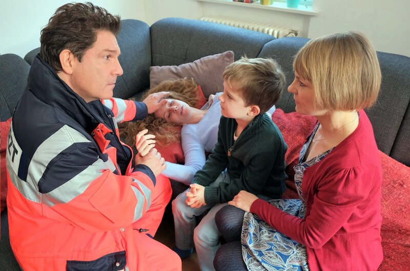 Notfall-Einsatz: Dr.Christian Kleist (Francis Fulton-Smith, l.) behandelt die schwerkranke Miriam Reichardt (Sina Valeska Jung, im HG). Die alleinerziehende Mutter sorgt sich um ihren Sohn Finn Reichardt (Hannes Gwiasda, 2.v.r.), ihre Nachbarin Ulrike Kern (Anna Hopperdietz, r.) kann sich nicht die ganze Zeit um das Kind kümmern. – Bild: ARD/​Jacqueline Krause-Burberg