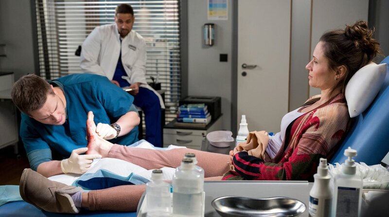 Unter den strengen Augen von Matteo Moreau (Mike Adler, h.) behandelt Mikko Rantala (Luan Gummich, l.) den blutenden Fuß von Helene Moschinsky (Daniela Preuß. r.). – Bild: ARD/​Jens-Ulrich Koch