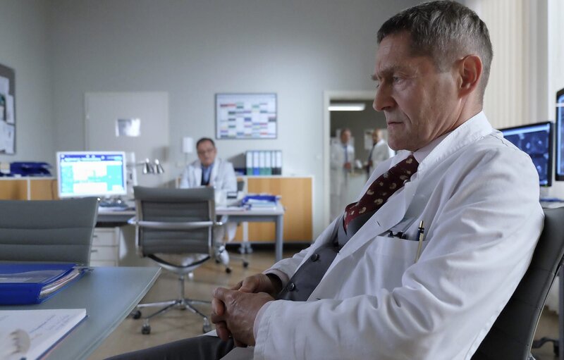 Dr. Kaminski (Udo Schenk, vorn) beschäftigt die Geschichte einer Patientin. Sie ist Escort-Girl und hat sich in einen älteren Mann verliebt, nun wartet sie darauf, dass er seine Frau verlässt. Als Hans-Peter Brenner (Michael Trischan, hinten) nach dem Grund für Kaminskis ungewohntem Interesse fragt, antwortet dieser, dass Wanda Schäfer ihn an seine Tochter erinnert. – Bild: BR/​MDR