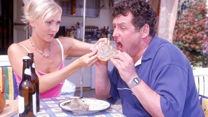Stefanie (Dana Golombek) versucht Benno (Willi Thomczyk) beizubringen, wie man vernünftig ein Leberwurst-Brot isst. – Bild: TVNOW /​ Frank Dicks