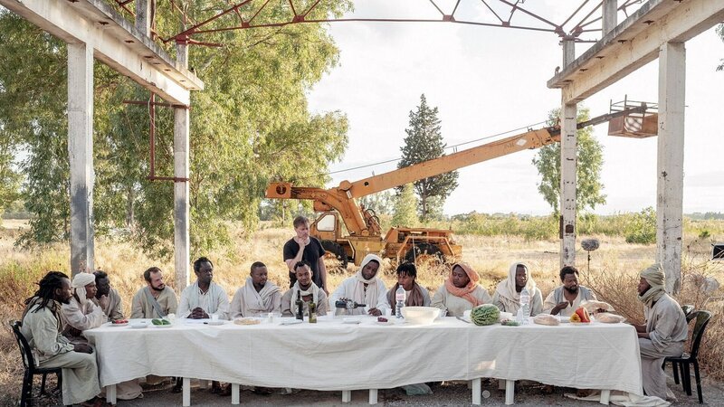 Jesus und seine Jüngerinnen (nicht im Bild) und Jünger bei der Vorbereitung für das letzte Abendmahl mit Regisseur Milo Rau im Hintergrund – Bild: Fruitmarket/Armin Smailovic Jesus und seine Jüngerinnen (nicht im Bild) und Jünger bei der Vorbereitung für das letzte Abendmahl mit Regisseur Milo Rau im Hintergrund – Bild: Fruitmarket/Armin Smailovic