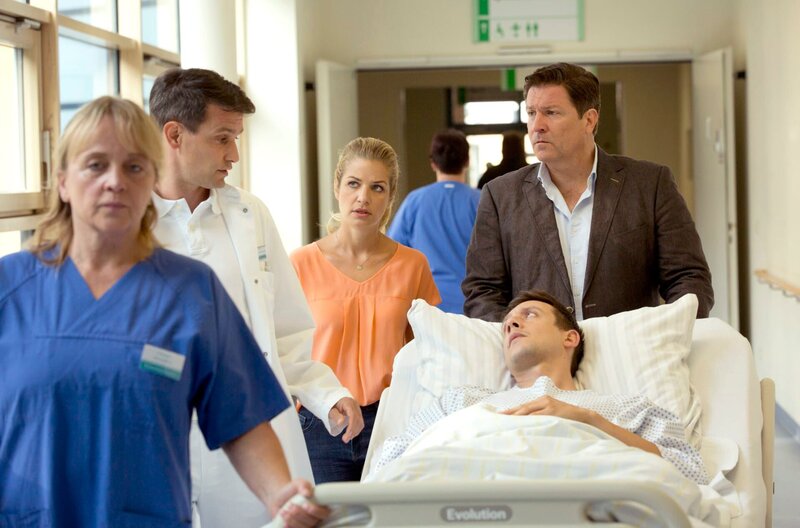 David wird von Dr. Sandmann in den OP gebracht. Seine Freundin Sara und Dr. Kleist begleiten ihn (v.l.n.r. Komparsin, Luca Zamperoni, Susan Sideropoulos, Francis Fulton-Smith, vorne Patrick Diemling). – Bild: ARD/​Volker Roloff