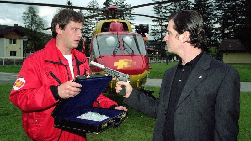Enrico Contini (Tom Mikulla, li.) übergibt Rainer Wörz (Fritz Karl) die Rohdiamanten im Austausch gegen das Plutonium. Doch der Erpresser spielt falsch. Er denkt nicht daran, sich an das Tauschgeschäft zu halten. Er will die Diamanten, das Plutonium und den Medicopter für seine Flucht. – Bild: RTL /​ Miguel Dieterich