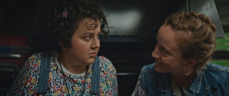 Marie-Josée (Salomé Diénis Meulien, l.) und Booby Mercury (Allison Chassagne, r.) sitzen in einem Food-Truck. Plötzlich wird der Wagen von einem Polizisten angehalten. – Bild: NOON
