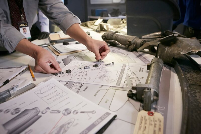 REENACTMENT – An investigator (played by a background performer) puts together the nuts and bolts found at the crash site and compares it to a diagram. (Photo Credit: Cineflex/​Ian Watson) – Bild: National Geographic Channel
