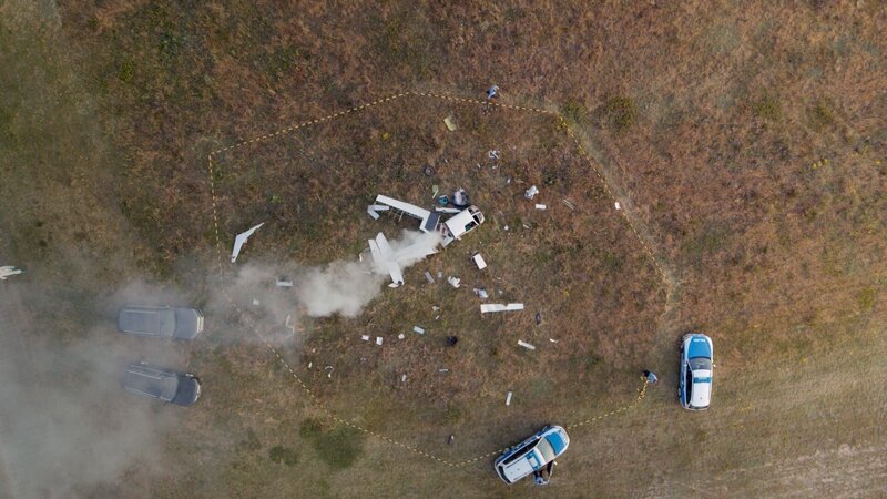 Auf einem Feld liegen die Wrackteile eines abgestürzten Sportflugzeugs. Aus einigen Teilen steigt vereinzelt Rauch hoch. Im Wrack liegt die Leiche des Piloten Philip Franke. Die Kriminalpolizei trifft am Tatort ein. – Bild: ZDF und Gordon Muehle