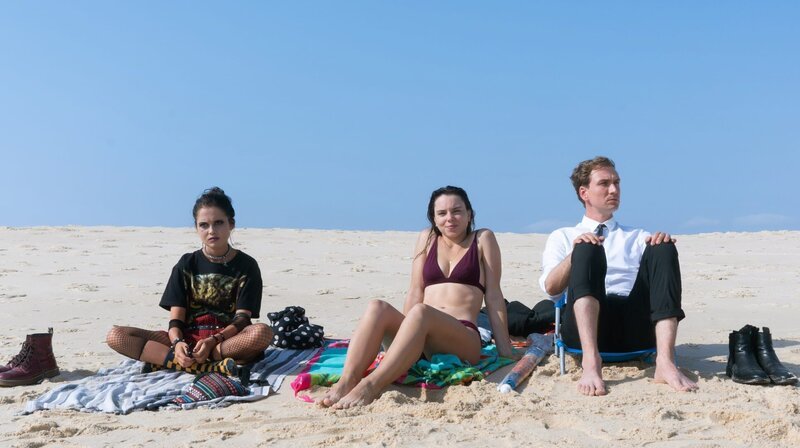 Zara (Bianca Nawrath, li.), Soraia Rosado (Filipa Areosa) und Leander Lost (Jan Krauter) verbringen gemeinsam einen Tag am Strand. – Bild: ARD Degeto/​Mariella Koch