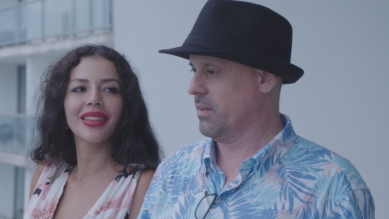 Gino and Jasmine on balcony of their luxury Panama apartment – Bild: Warner Bros. Discovery, Inc. or its subsidiaries and affiliates.