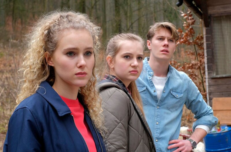 Luisa Ewald (Pauline Angert, l.) , Lotte Ewald (Anne Sophie Triesch, M.) und Lenny Krause (Richard Kreutz, r.) beobachten, wie Max im Rettungswagen abtransportiert wird. – Bild: ARD/​Jacqueline Krause-Burberg