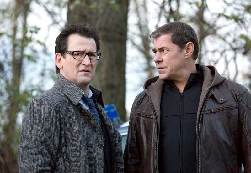 Ein Medium berichtet aufgeregt von einem Mädchen, das in einem roten Grab um sein Leben kämpfen soll. Die Ermittler Lars Englen (Ingo Naujoks, l.) und Finn Kiesewetter (Sven Martinek, r.) machen sich auf den Weg, um die Mutter des Mädchens zu befragen. – Bild: NDR/​ARD/​Georges Pauly