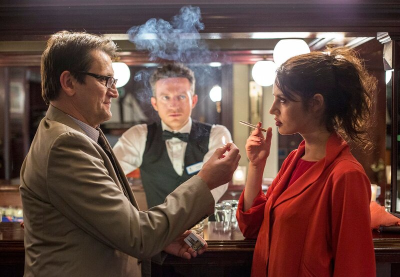 Lars Englen (Ingo Naujoks, l.) erinnert sich, das Mordopfer Ruby Engel (Violetta Fazjija, r.) an der Hotelbar getroffen zu haben. Sie war die Freundin des Barkeepers Max (Josef Heynert, M.), hat aber auch Kontakt zu fremden Männern gesucht. – Bild: NDR/​ARD/​Georges Pauly