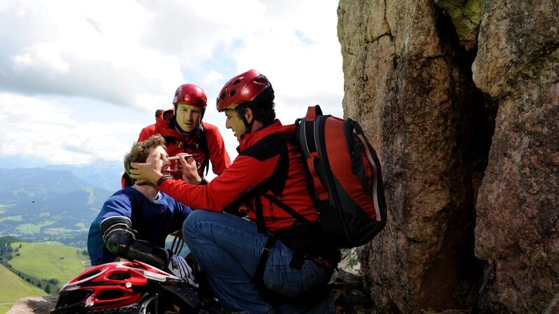 Simon Brandl (Constantin Gastmann, l.) ist mit dem Mountainbike gestürzt und wird von Hans Gruber (Heiko Ruprecht, M.) und Dr. Martin Gruber (Hans Sigl, r.) erstversorgt. – Bild: ZDF und Thomas R. Schumann