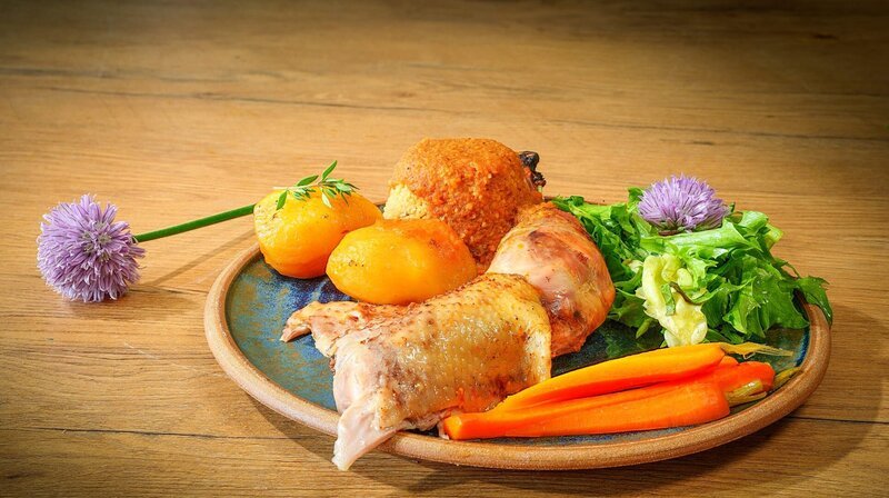 Im Hauptgang gibt es einen Bruderhahn aus dem Römertopf, garniert mit Kartoffeln vom eigenen Acker, knackigem Salat, Möhren und aromatisch gewürztem Couscous. – Bild: NDR/​Doclights/​Marc Vorwerk