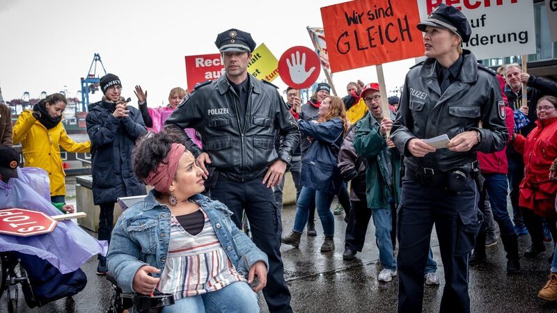 Melanie (Sanna Englund, r.) und Mattes (Matthias Schloo, 2.v.l.) müssen zu einer unangemeldeten Demo, die von der Aktivistin Cora Liberti (Kübra Sekin, l.) organisiert wurde. (Rest: Komparsen). – Bild: ZDF und Boris Laewen (bola)