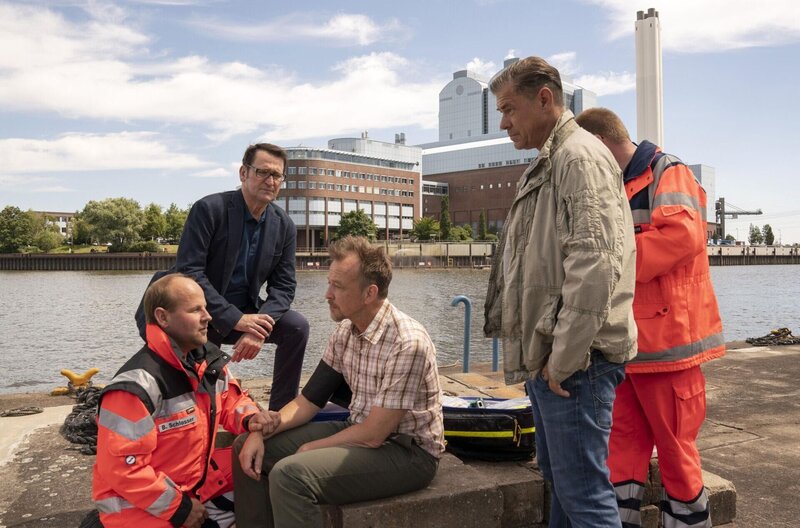 Alexander Hoffmann, ein Ex-Trinker, wurde in seinem Haus am Wasser niedergestochen und tödlich verletzt. Die Lübecker Ermittler Finn Kiesewetter (Sven Martinek, r.) und Lars Englen (Ingo Naujoks, 2.v.l.) müssen das Verbrechen aufklären. Was hat Bernd Reuter (Christian Bruhn, 3.v.l.) damit zu tun. – Bild: Degeto Film GmbH | OneGate Media GmbH