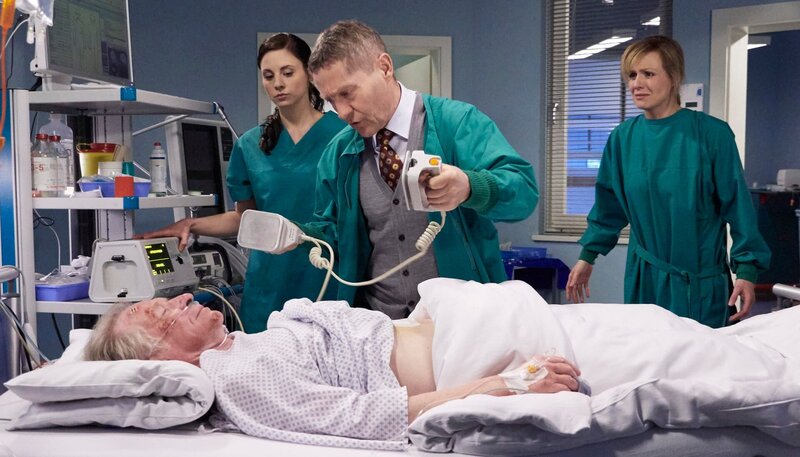Dr. Lea Peters (Anja Nejarri, re.) hat die ganze Nacht am Bett ihres Vaters Ludwig (Hermann Beyer, liegend) verbracht. Doch plötzlich schlagen die Monitore Alarm, Ludwigs Kreislauf ist zusammengebrochen. Die sonst so sachliche und rationale Lea ist völlig verzweifelt und handlungsunfähig. Dr. Kaminski (Udo Schenk, mi.) und Schwester Nadine Meyer (Julia Schäfle, li.) übernehmen die Reanimation. – Bild: MDR/​Rudolf Wernicke
