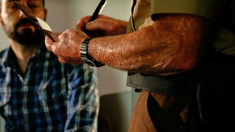 Der Detektiv schreibt den Bericht, während sich der Mann hinsetzt. – Bild: Crime + Investigation