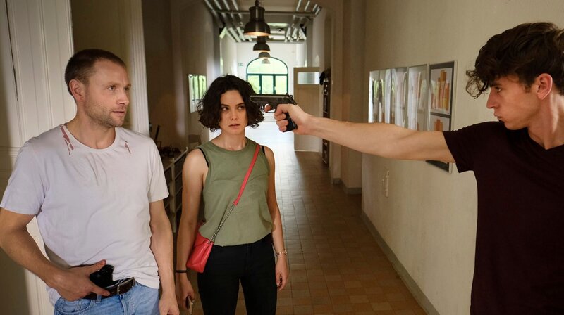 Nico (Emil Belton) ergreift die Chance: Er hat sich die Waffe genommen und bedroht Louis (Max Riemelt) und Anna Bürger (Katia Fellin). – Bild: MDR/​W&B Television/​Michael Kotschi