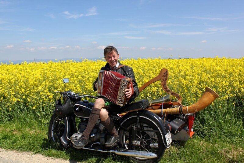 Stofferl Well schwingt sich mal wieder auf sein altes Motorrad, packt möglichst viele Instrumente in den Beiwagen und geht seiner Lieblingsbeschäftigung nach: Er strawanzt durch Bayern. – Bild: BR