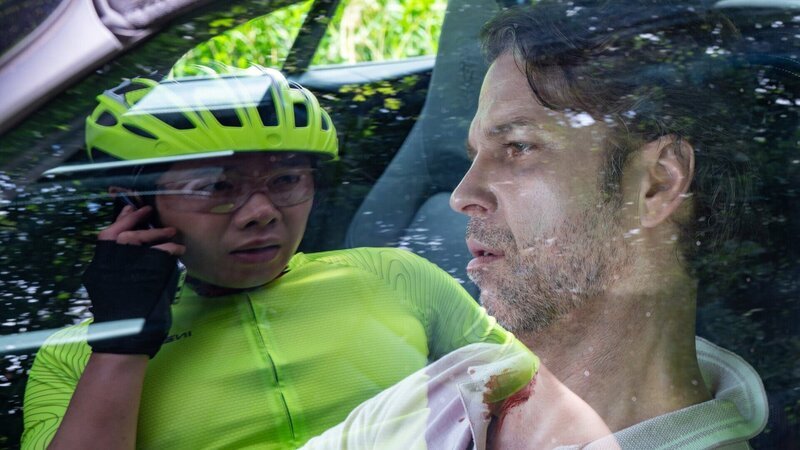 Thomas Brandner (Yung Ngo, l.) radelt durch den Wald bis er nach einer Kurve fast gegen ein Auto fährt. Er will die Person (Ingmar Grapenbrade, r.) im Auto zur Rede stellen, doch die ist tot. – Bild: ZDF und Fotografin: Britta Krehl