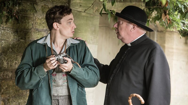 Lewis Ward (Thomas Pickles, l.) liebt es zu fotografieren. Als er einen schlafenden Mann ohne sein Wissen ablichtet, hält Father Brown (Mark Williams, r.) ihn auf. Welche seltsamen Eigenschaften verbirgt der geheimnisvolle Junge außerdem noch? – Bild: ZDF