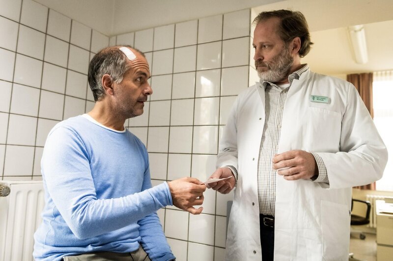 Tilo (Christoph Maria Herbst) lässt sich am Kopf verarzten, sein Arzt (Benjamin Höppner) ist der Mann von Caroline Schub. – Bild: RTL /​ Martin Valentin Menke