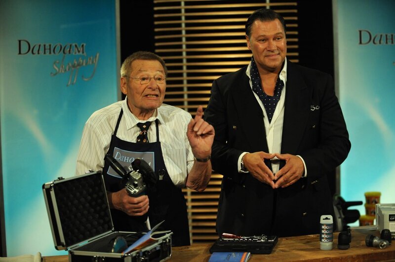 Alois preist beim Teleshoppingkanal die Produkte gekonnt an. Von links: Alois Preissinger (Erich Hallhuber sen.) und TV-Moderator Baumann (Robert Jarczyk). – Bild: BR/​Marco Orlando Pichler
