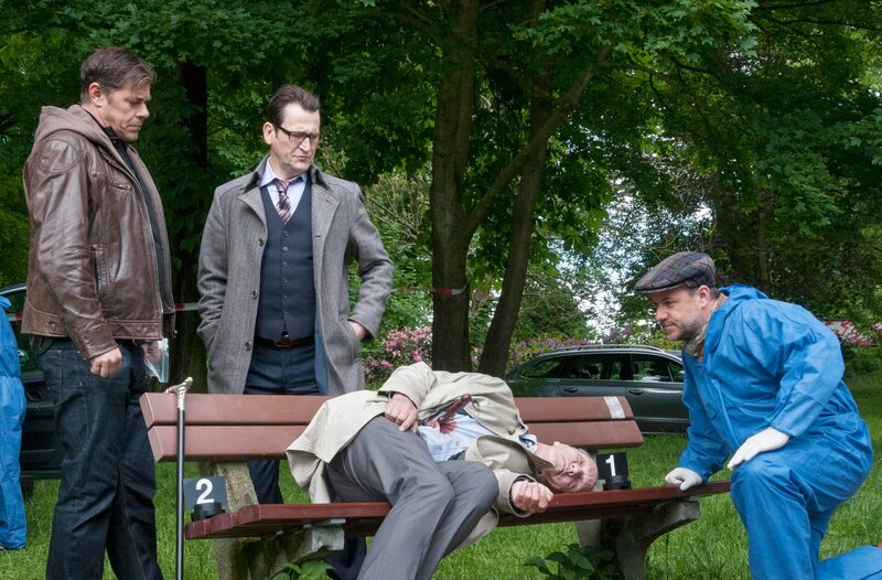 Gerichtsmediziner Dr. Strahl (Christoph Tomanek, r.) und die Kommissare Finn Kiesewetter (Sven Martinek, l.) und Lars Englen (Ingo Naujoks, 2.v.l.) am Tatort mit Lasse Hellgards (Thomas Bestvater, liegend) Leiche. – Bild: ARD/​Georges Pauly