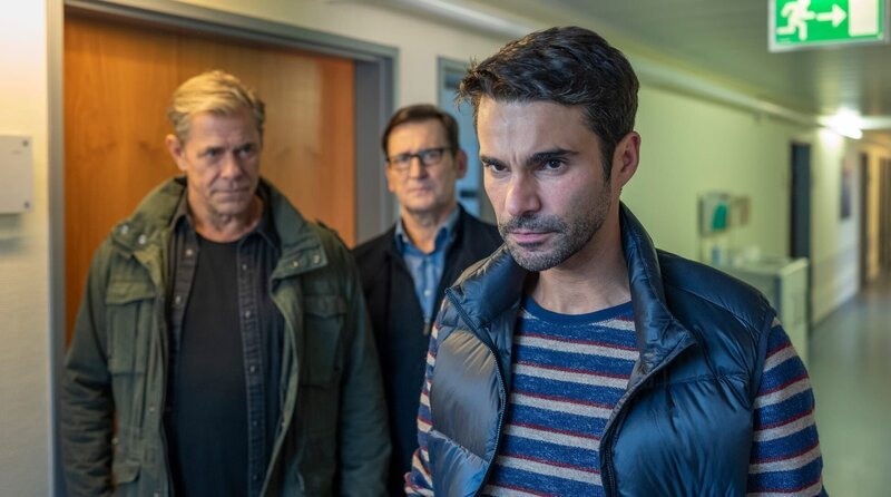Ivo Struck (Luka Dimić, r.) kann nicht fassen, dass jemand versucht hat, seine Ehefrau Anna umzubringen. Den Kommissaren Finn (Sven Martinek, l.) und Lars (Ingo Naujoks, h.M.) gegenüber äußert er einen Verdacht … – Bild: ARD/​Thorsten Jander