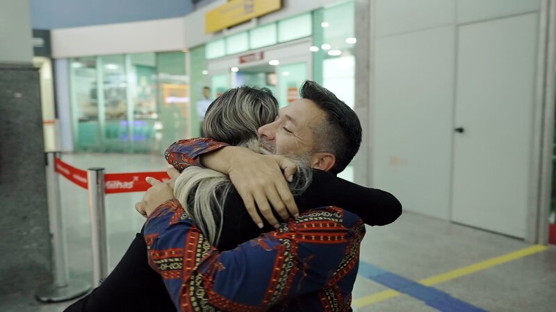 In the airport, Brian Muniz and Ingrid Rezende Dos Santos hug, meeting for the first time. – Bild: Warner Bros. Discovery, Inc.