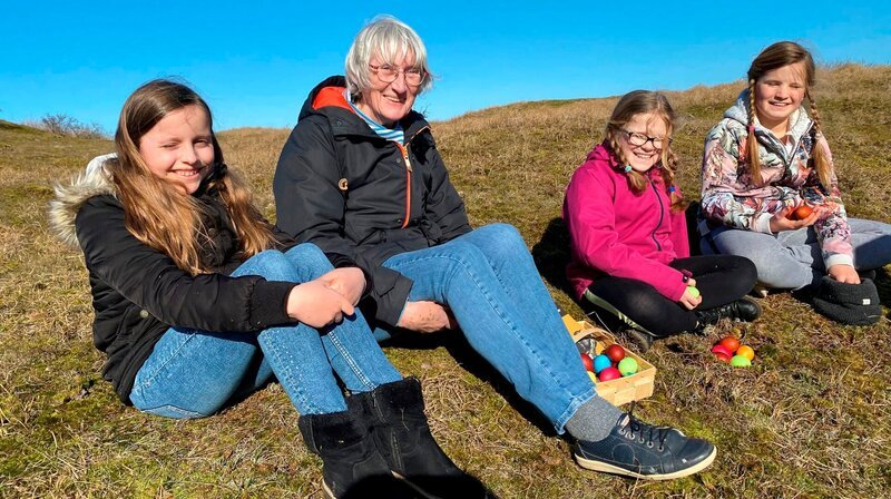 Osterbräuche auf der Insel. Auf Baltrum trafen sich die Insulaner in jedem Jahr an der Osterdüne zum „Eiertrullern“ und „Eierbicken“. Insulanerin Anneliese Junker erklärt den Mädchen aus der Inselschule, wie das geht. Namen der Mädchen v.l.n.r.: Laura Possekel, Anneliese Junker, Juliane Wagner, Lientje Otto – Bild: NDR/​Katrin Heineking