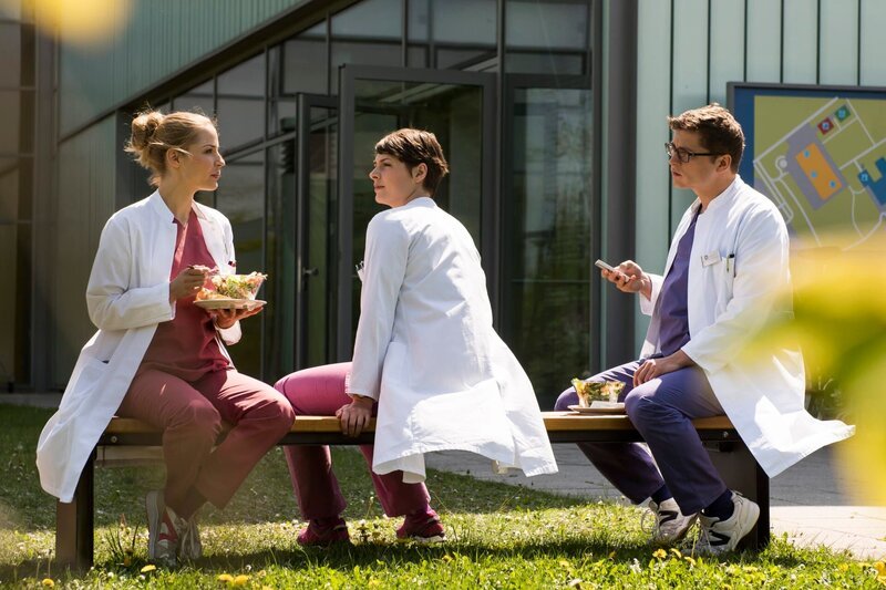 In ihrer Mittagspause versucht Julia Theresa wegen der Affäre mit Klinikchef Wolfgang Berger auf den Zahn zu fühlen. Theresa findet andere Gründe warum sie nicht gefeuert wurde. Julia ist stinksauer. V.l.n.r. Julia Berger (Mirka Pigulla), Dr. Theresa Koshka (Katharina Nesytowa), Elias Baehr (Stefan Ruppe). – Bild: ARD/​Jens Ulrich Koch
