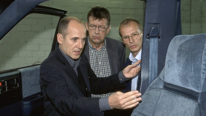Gemeinsam erläutern Dr. Robert Kolmaar (Ulrich Mühe, l.), Joe Hoffer (Jörg Gudzuhn, M.) und der Unfallsachverständiger Walter Erhardt (Jens-Uwe Bogadtke, r.) ihre Untersuchungsergebnisse am Unfallauto von Helga Rossberg. – Bild: ZDF und Katrin Knoke