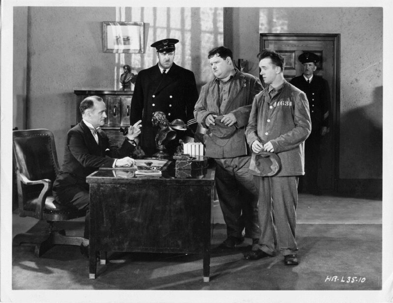 Stan (Stan Laurel – zweiter von rechts) und Ollie (Oliver Hardy – dritter von rechts) sind wegen Alkoholverkaufs verhaftet worden und werden dem Gefängnisdirektor Warden (Wilfred Lucas – links) vorgeführt. – Bild: ZDF und Jack Stevens