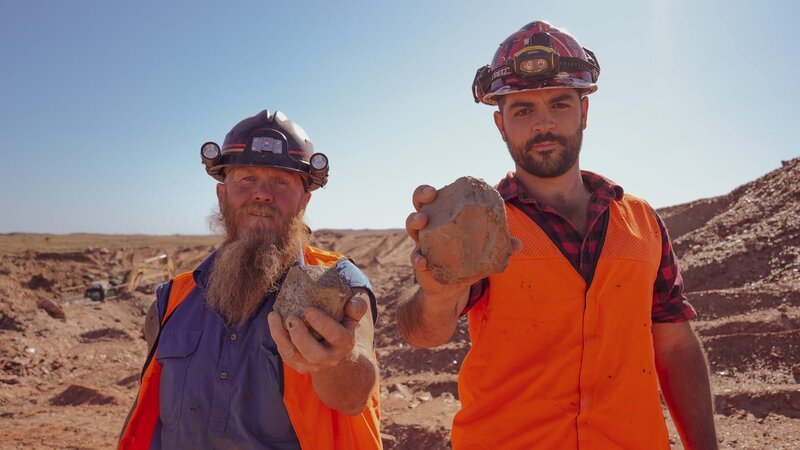 James ‚JC‘ Caruana and Rod Manning holding up a garnet to the camera in a garnet mine. – Bild: 2024 Warner Bros. Discovery, Inc. or its subsidiaries and affiliates. All rights reserved.