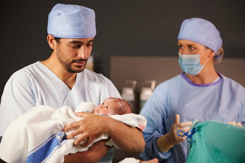 Nach einem gelungenen Kaiserschnitt, kann Hebamme Lena Lorenz (Judith Hoersch) Ben Tewolde (Timo Fakhravar) seine kleine Tochter in den Arm legen. – Bild: ZDF und Walter Wehner.