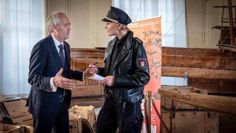 Prof. Munze (Heiner Hardt) ist außer sich. Der Ahnenschädel, das wichtigste Exponat seiner Ausstellung, wurde gestohlen. Melanie (Sanna Englund) nimmt die Einzelheiten auf. – Bild: ZDF und Boris Laewen
