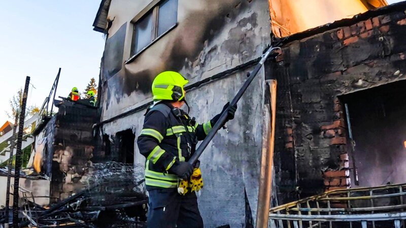 Ein Feuerwehrmann reißt eine Dachrinne an einem ausgebrannten Haus ab – Bild: Warner Bros. Discovery, Inc. or its subsidiaries and affiliates.